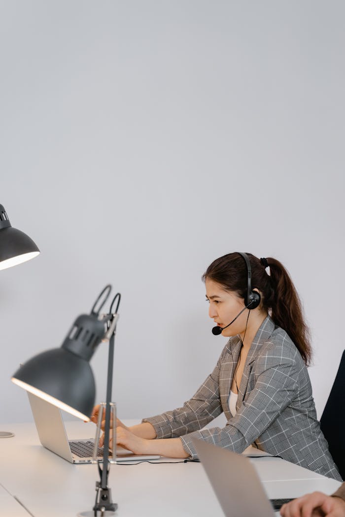 Businesswoman wearing a headset working on a laptop in a modern call center office.